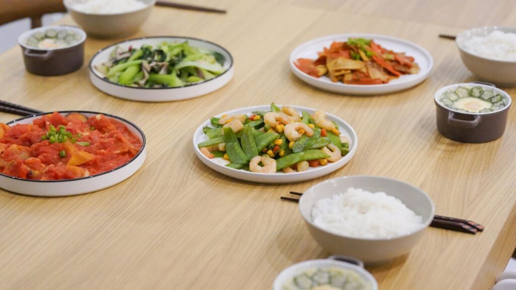 A plated portion of the stir-fry next to a bowl of fluffy rice.